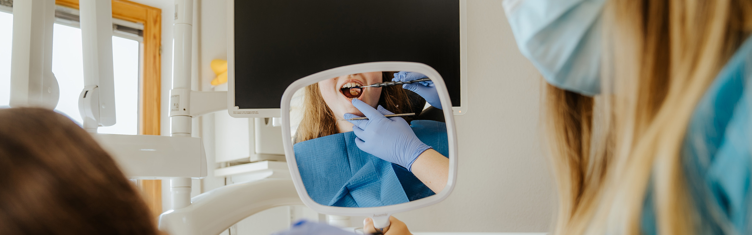 Füllungstherapie - Die Patientin schaut sich ihre Zähne in einem Spiegel an in der Zahnarztpraxis Frank Kruse in Wutöschingen-Horheim